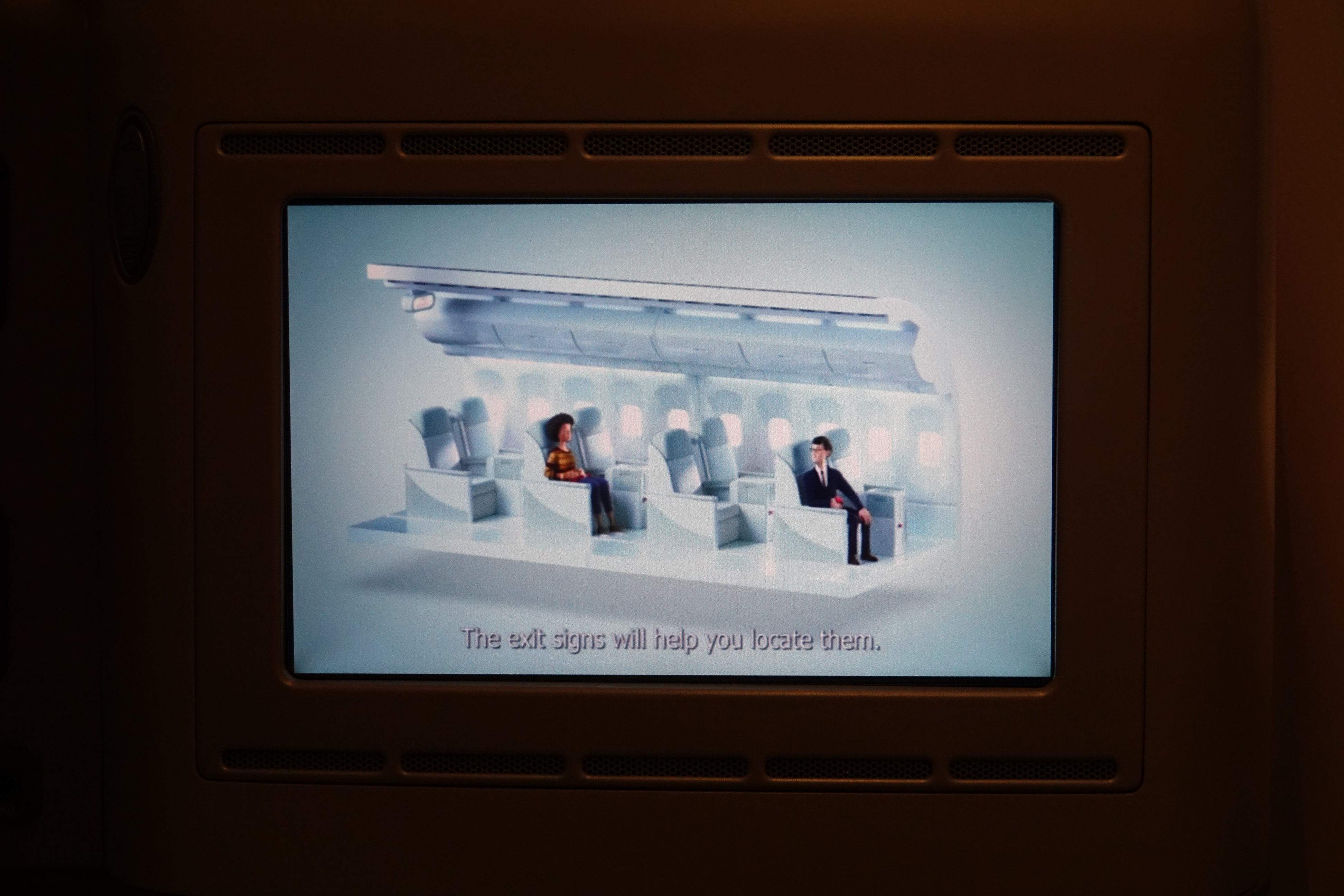 a screen showing a man and woman sitting in an airplane