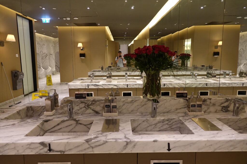 a bathroom with marble counter tops and red flowers