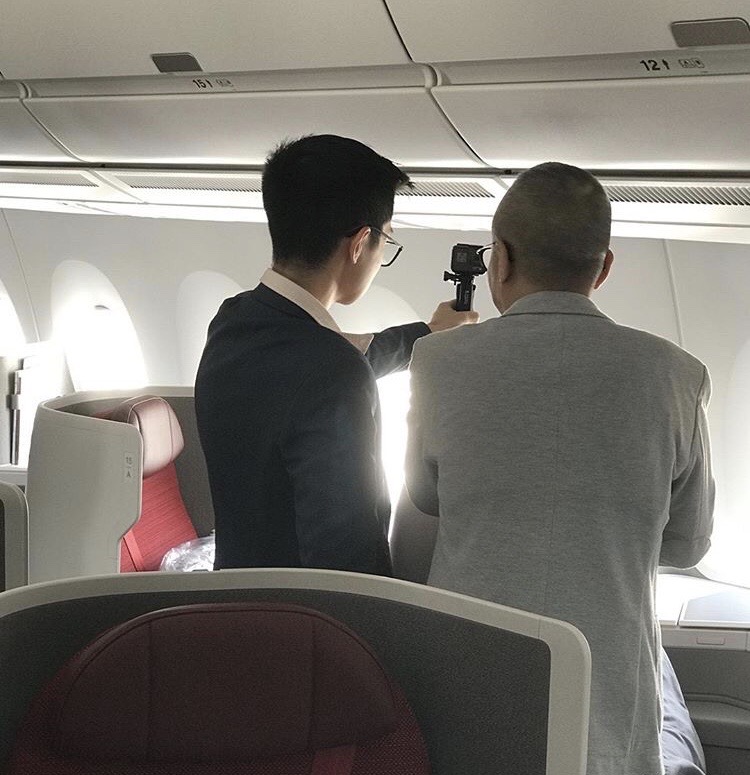 a man taking a picture of another man on an airplane