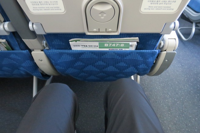 a person's legs in a seat with a blue seat cover
