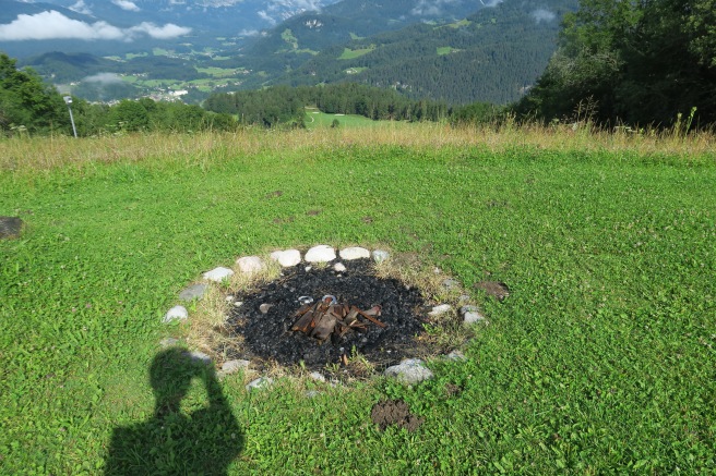 a fire pit in a grassy area with a mountain range in the background