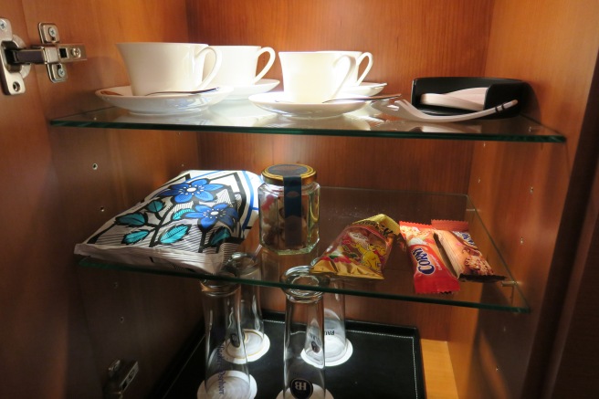 a glass shelf with cups and other items