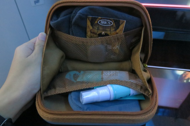 a hand holding a small brown bag with items inside