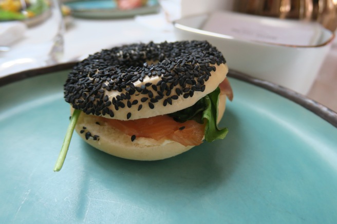 a bagel with black sprinkles on a blue plate
