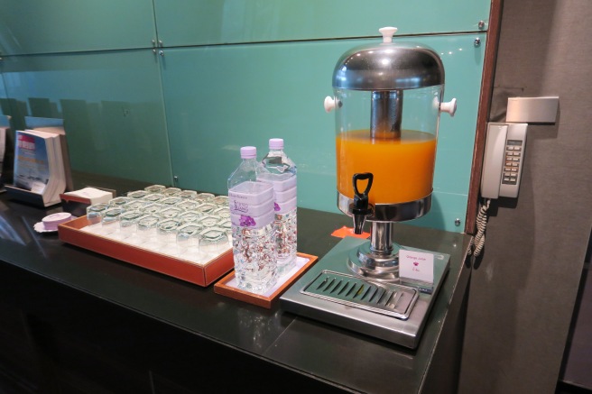 a juice dispenser and bottles of water