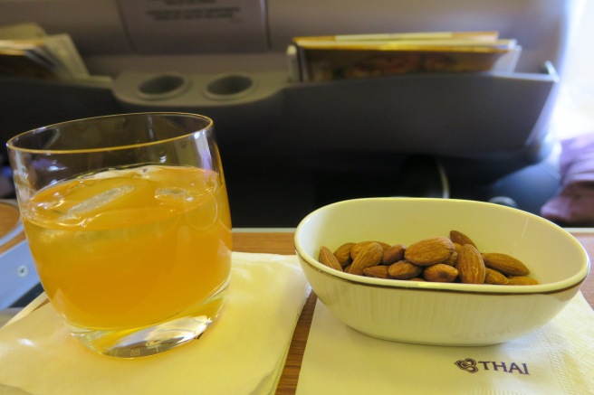 a bowl of almonds and a glass of orange juice on a table