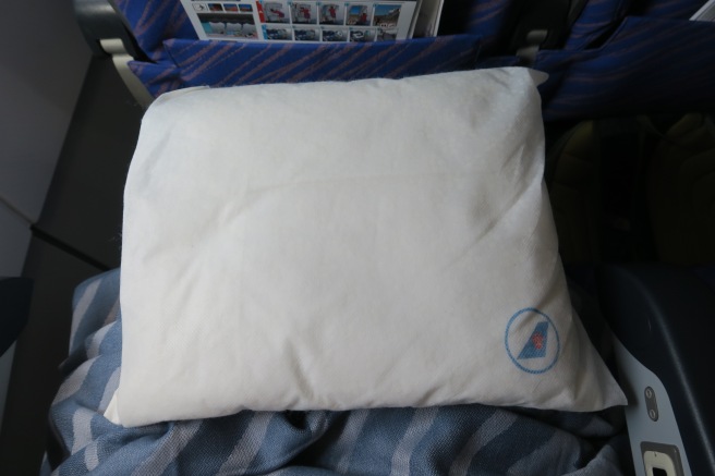 a white pillow on a blue and white striped blanket