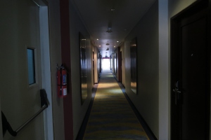 a long hallway with doors and a fire extinguisher