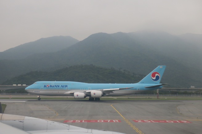 a blue airplane on a runway with mountains in the background