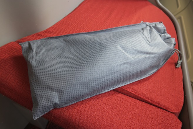 a grey bag on a red cushion