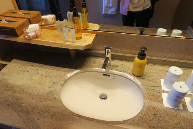 a sink with soap and bottles on a shelf