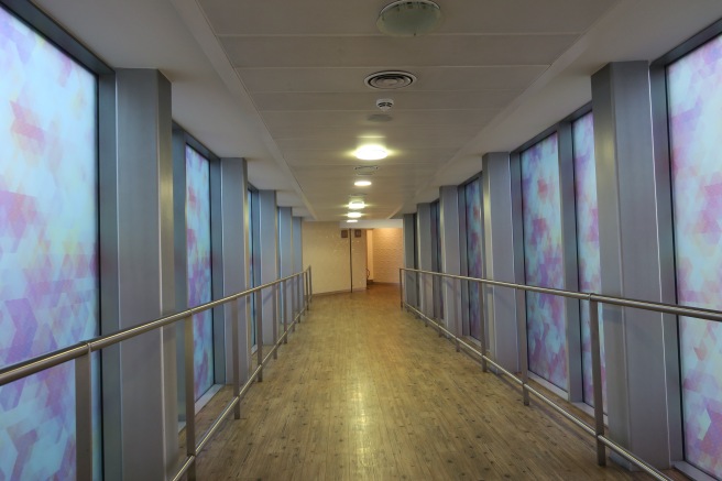 a long hallway with a handrail and a wood floor
