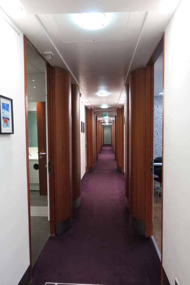 a hallway with purple carpet and wood pillars