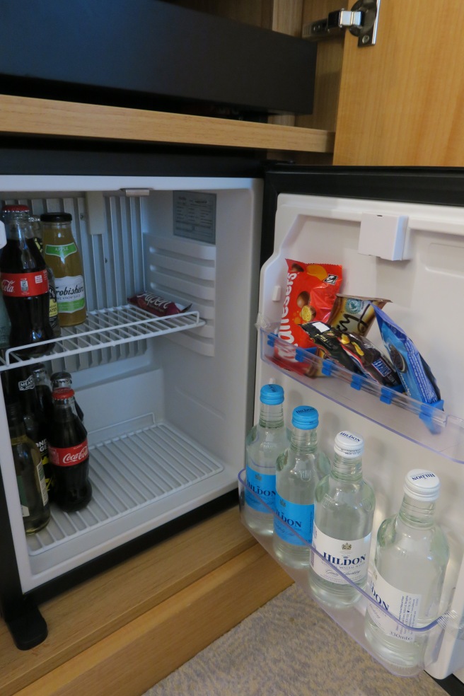 a mini fridge with bottles of soda and snacks
