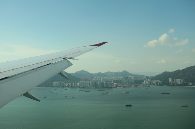 an airplane wing over water with city in the background