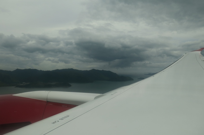 a view of the wing of an airplane over water and mountains