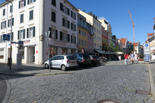 a group of cars parked on a cobblestone street