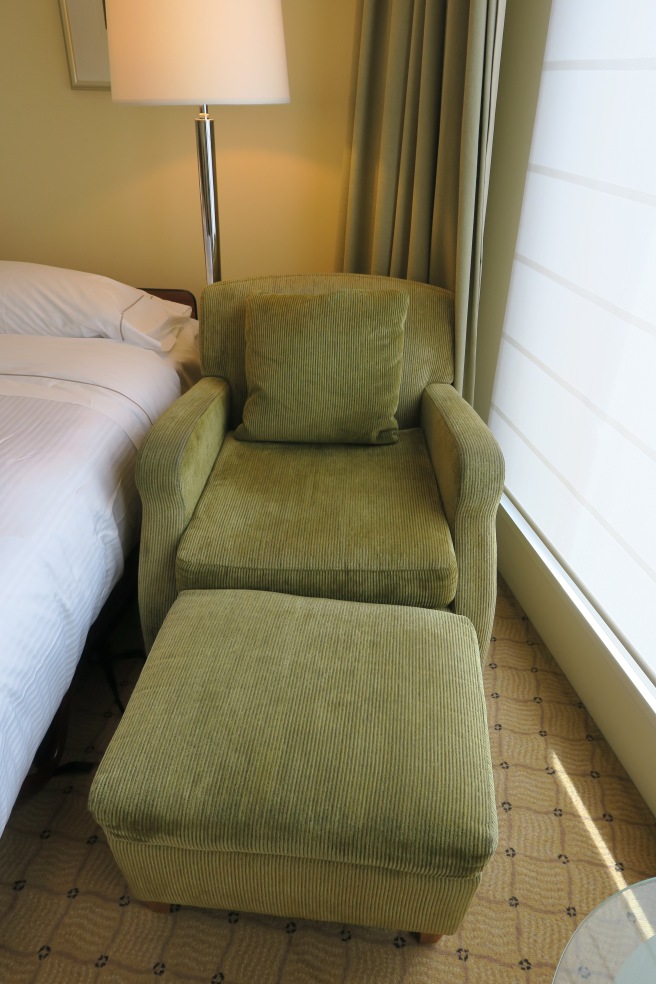 a green chair and ottoman in a hotel room