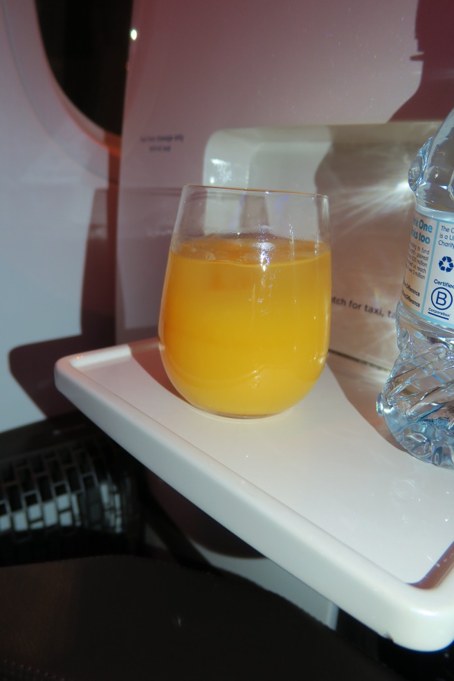 a glass of orange juice on a white tray