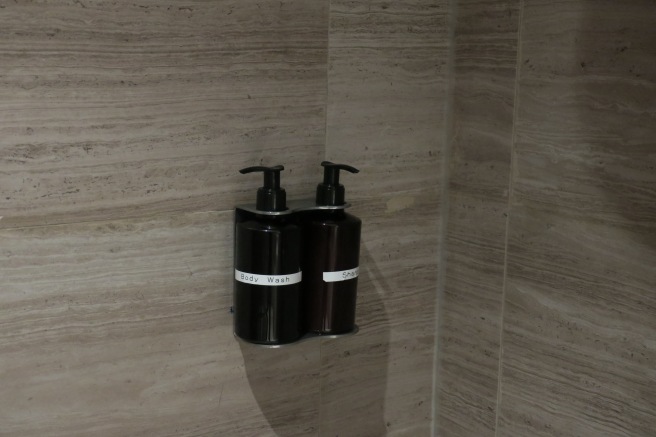 a couple of black soap dispensers on a wall
