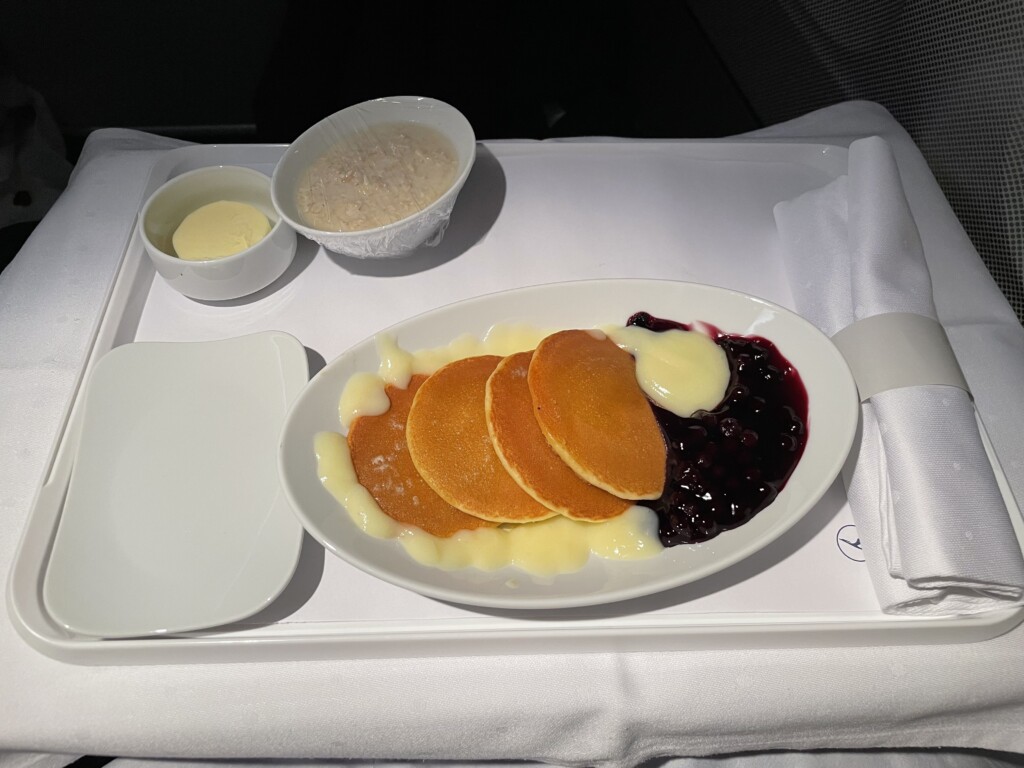 a plate of pancakes with blueberry jam and a bowl of rice