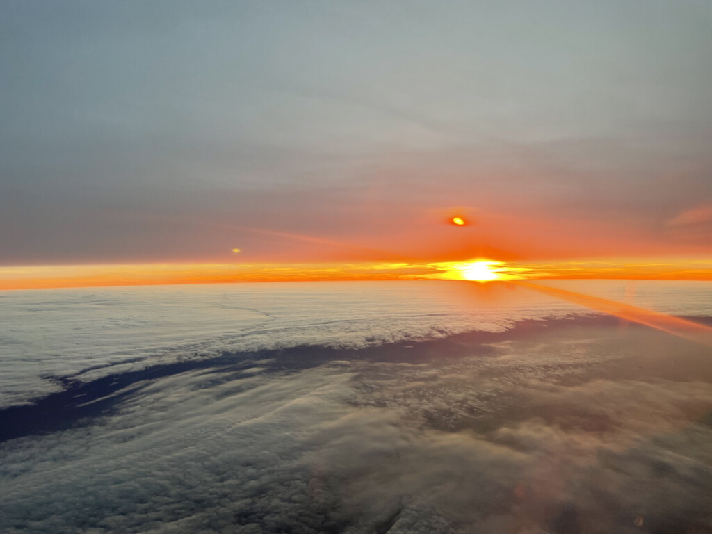 a sunset over clouds and a body of water