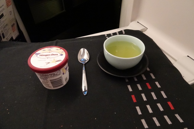 a cup of green liquid and a spoon on a black surface