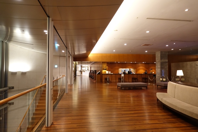 a lobby with a glass wall and a wooden floor