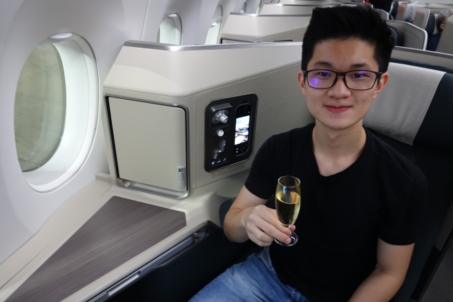 a man sitting in an airplane holding a glass of champagne