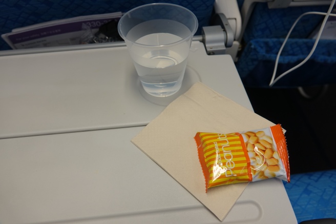 a small package of peanuts and a glass of water on a table