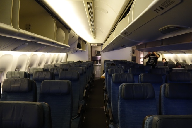 an inside of an airplane with seats and a man standing in the back