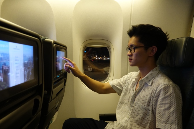 a man sitting in an airplane looking at a screen