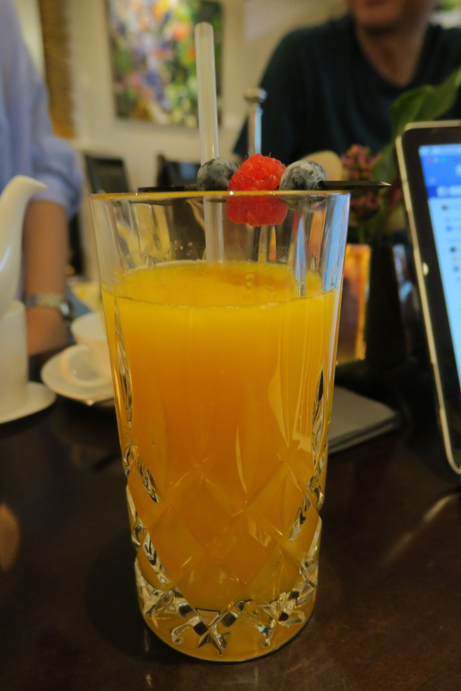 a glass of orange juice with a straw and berries