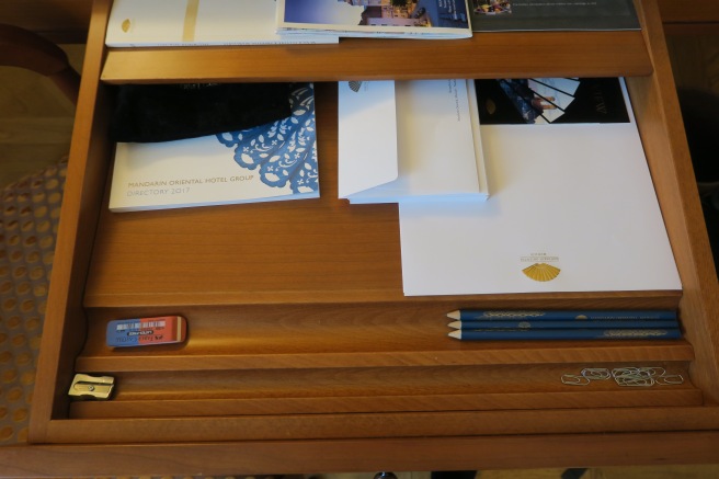 a desk with a drawer full of papers and pencils