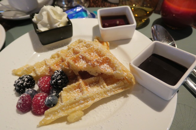 a plate of waffles with berries and syrup
