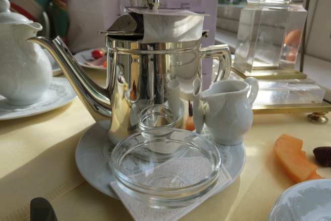 a silver teapot and glass dishes on a table