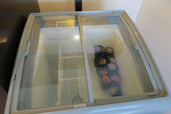 a refrigerator with a basket and cans inside