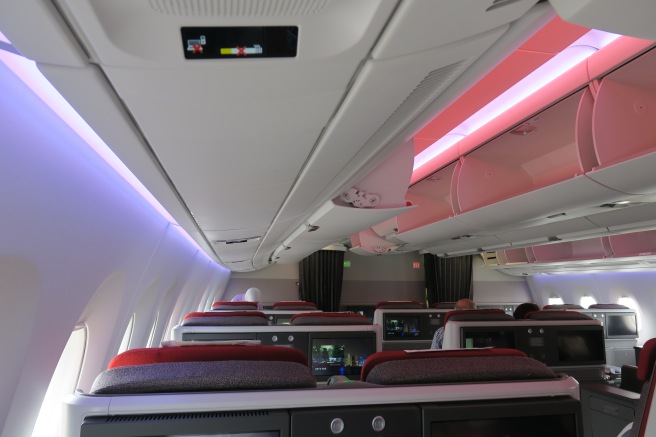 the inside of an airplane with seats and a pink light