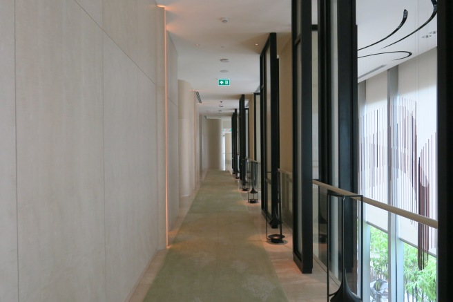 a long hallway with glass walls and a railing