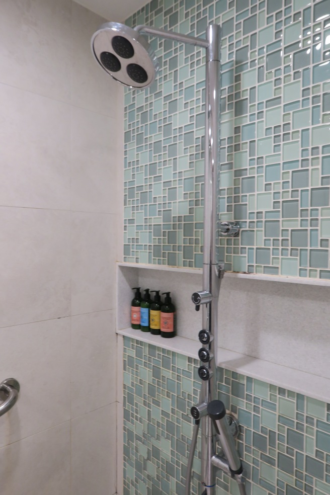 a shower with a tile wall and a shower head