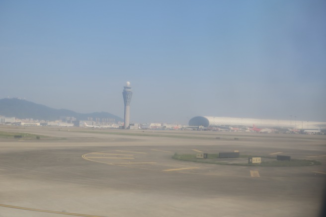 an airport runway with a tower and buildings in the background