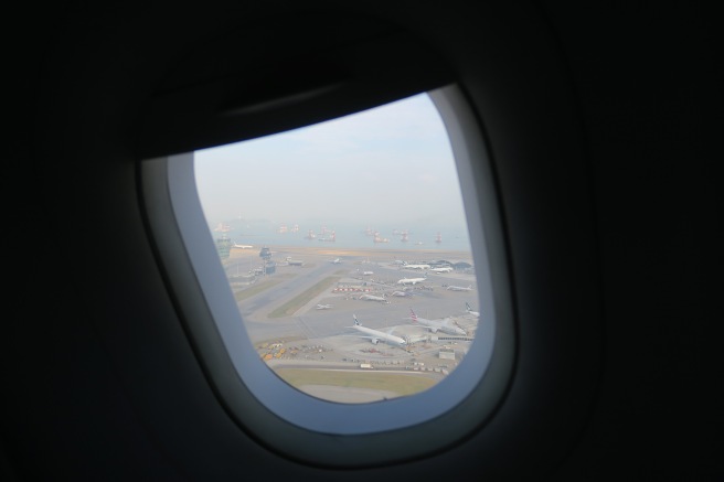 an airplane window with many airplanes on the runway