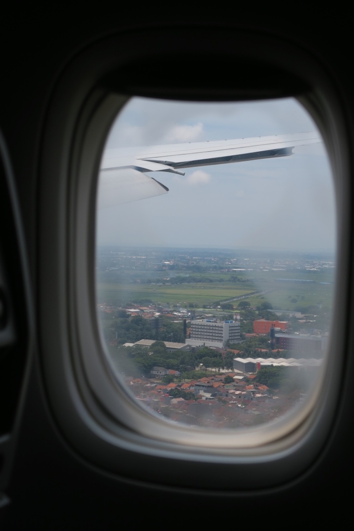 an airplane window with a view of a city and buildings