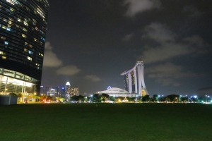 a green field with tall buildings in the background