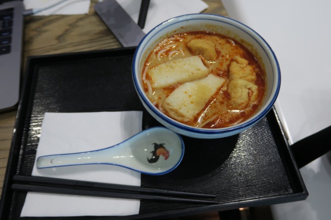 a bowl of soup with chopsticks and a spoon