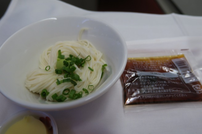 a bowl of noodles and a packet of sauce