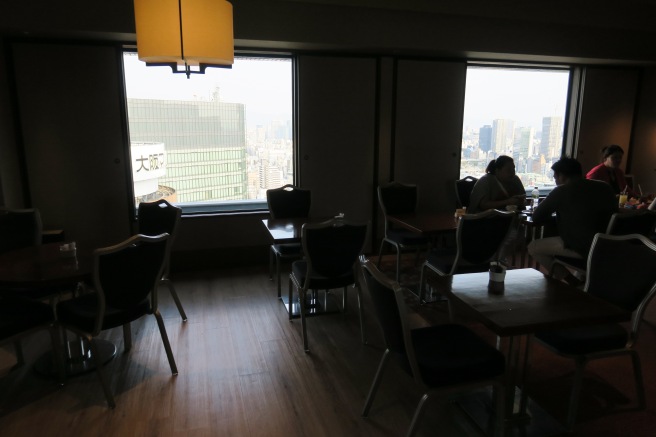 a room with tables and chairs and a window with a city view
