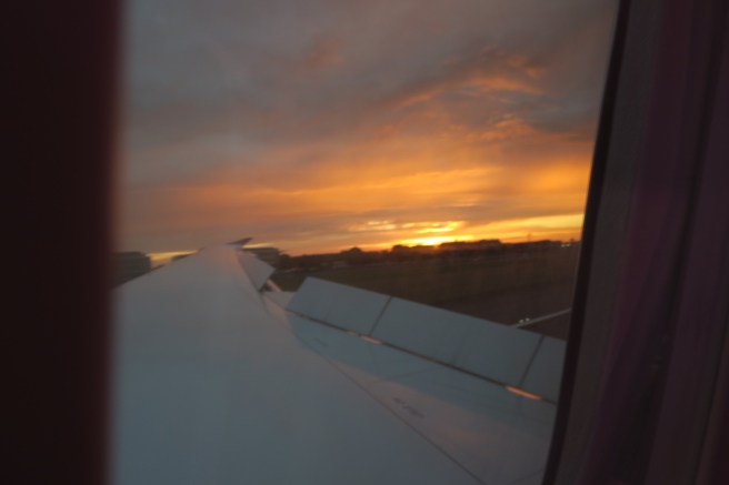 an airplane wing and the sun setting
