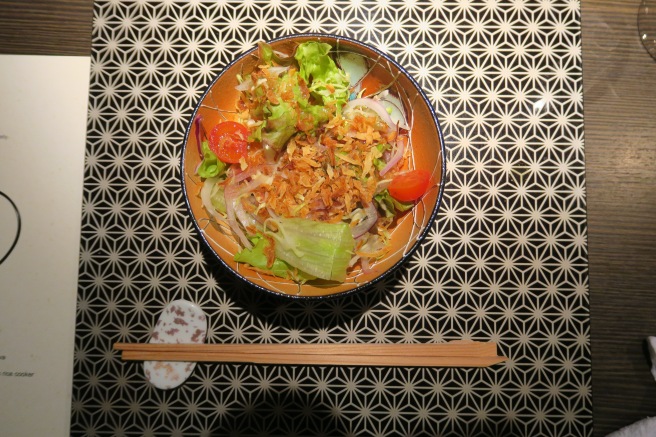 a bowl of salad with chopsticks