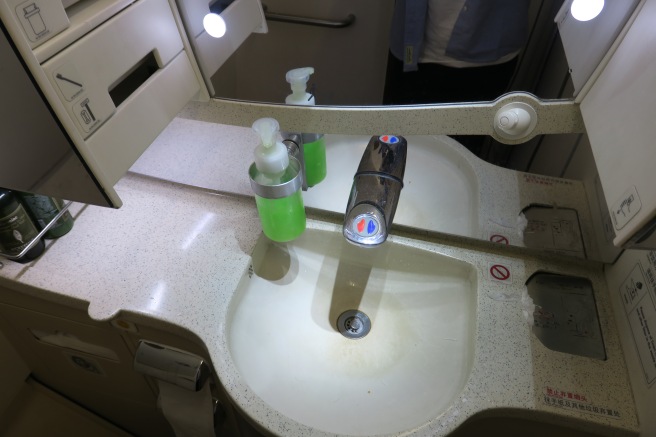 a sink with soap dispenser and a mirror